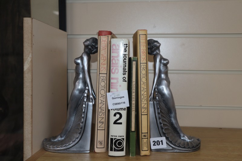 A pair of silvered resin bookends and four books: The Journals of Anais Nin, Under The Hill, Little Birds Erotica by Anais Nin and Delt